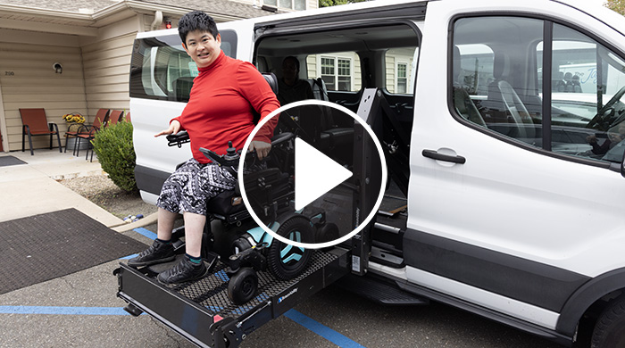 Ali from Rose House is lifted into a specialized transport van.